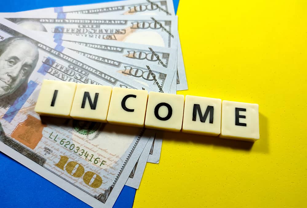 Selective focus.Banknotes with word income on blue and yellow background.Business concept.